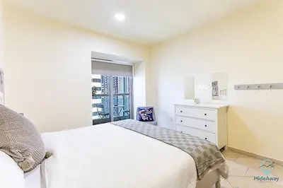 a white bedroom with a white bed and a window at 1 BR Blue Chic Dubai Marina, Steps to Beach! in Dubai