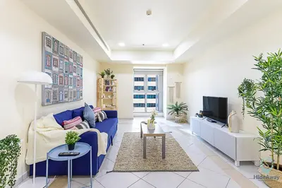 a living room with a blue couch and a tv at 1 BR Blue Chic Dubai Marina, Steps to Beach! in Dubai
