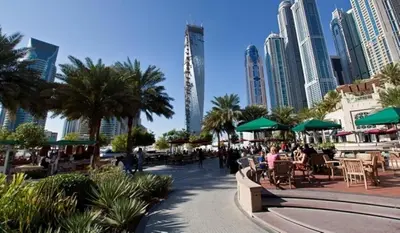 a city with people sitting at tables and green umbrellas at 1 BR Blue Chic Dubai Marina, Steps to Beach! in Dubai