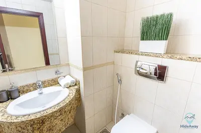a bathroom with a sink and a toilet and a mirror at 1 BR Blue Chic Dubai Marina, Steps to Beach! in Dubai