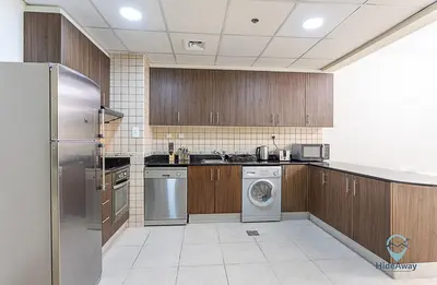 a kitchen with stainless steel appliances and wooden cabinets at 1BR Charming Modern 5Min to Beach Dubai Marina in Dubai