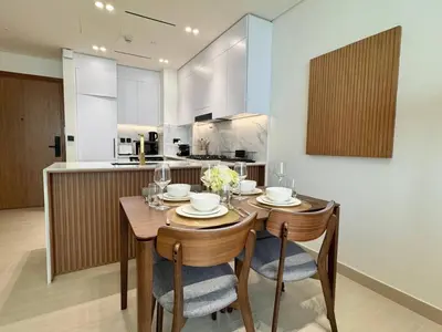 a kitchen with a wooden table with chairs and a dining room at Tranquil 1br Retreat Stylish Stay In Jvc in Dubai