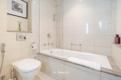 a white bathroom with a toilet and a bath tub at Premium 2BR Apartment in Paramount Tower with City Skyline Views in Dubai