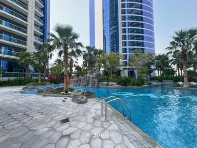 a swimming pool with palm trees and buildings at Premium 2BR Apartment in Paramount Tower with City Skyline Views in Dubai