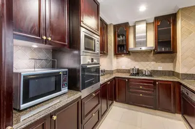 a kitchen with wooden cabinets and stainless steel appliances at Durrani Homes - Luxe Living at Souk Al Bahar with Burj Khalifa and partial Fountain view in Dubai