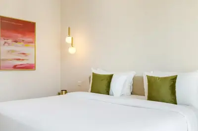 a bedroom with a large white bed with green pillows at Durrani Homes - Luxe Living at Souk Al Bahar with Burj Khalifa and partial Fountain view in Dubai
