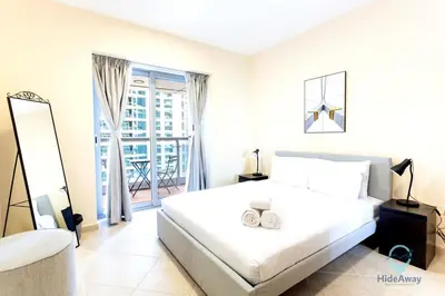 a white bedroom with a large bed and a window at 1BR Cool Vibes Pool Views Dubai Marina in Dubai