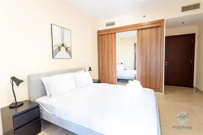 a bedroom with a white bed and a sliding glass door at 1BR Cool Vibes Pool Views Dubai Marina in Dubai