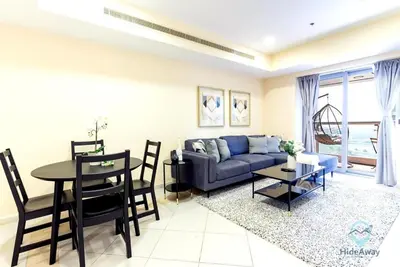 a living room with a blue couch and a table at 1BR Cool Vibes Pool Views Dubai Marina in Dubai