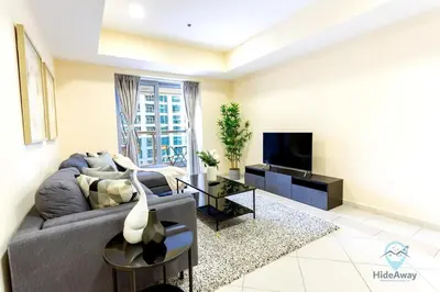 a living room with a gray couch and a tv at 1BR Cool Vibes Pool Views Dubai Marina in Dubai