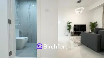 a white bathroom with a toilet and a tv at Spacious and Bright Retreat in JBR in Dubai
