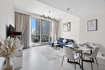 a living room with a table and a blue couch at VayK - Luxury 1BR in Downtown in Dubai