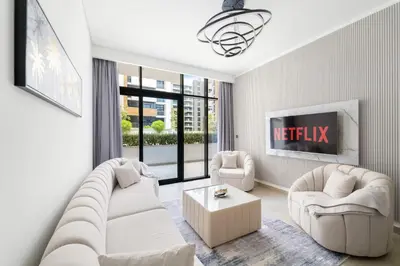 a living room with white furniture and a tv at VayK - Modern 3BR with a Spacious Terrace in Dubai