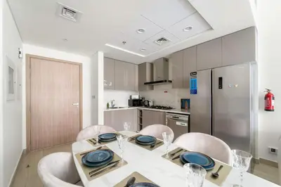 a dining room with a table and chairs and a kitchen at VayK - Modern 3BR with a Spacious Terrace in Dubai