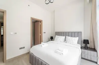 a bedroom with a large white bed with two chairs at VayK - Modern 3BR with a Spacious Terrace in Dubai