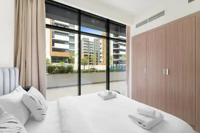 a bedroom with a white bed and a large window at VayK - Modern 3BR with a Spacious Terrace in Dubai