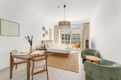 a living room with a bed and a table and chairs at VayK - Stylish & Cozy Studio in JVC in Dubai
