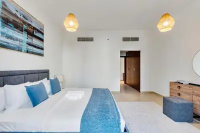 a bedroom with a large white bed with blue pillows at Enchanting Stay in JBR Near The Beach in Dubai