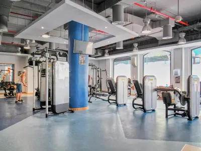 a gym with cardio machines and a woman in the background at Enchanting Stay in JBR Near The Beach in Dubai