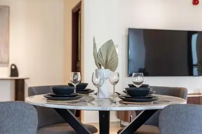 a table with plates and wine glasses and a tv at Enchanting Stay in JBR Near The Beach in Dubai
