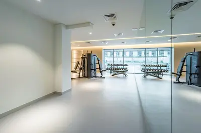 an empty room with a gym with benches and machines at City Views 1BR with Balcony Near Mall, Concept 7 Residences, Jumeirah Village Circle by Deluxe Holiday Homes in Dubai