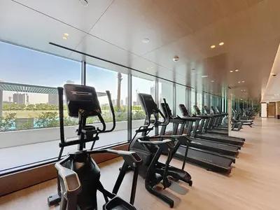 a row of treadmills in a gym with a large window at Binghatti Onyx - Upgraded One Bedroom in JVC in Dubai