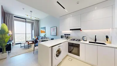 a kitchen with white cabinets and a washer and dryer at Binghatti Onyx - Upgraded One Bedroom in JVC in Dubai