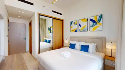 a bedroom with a large white bed with blue pillows at Binghatti Onyx - Two Bedroom with Private Pool in Dubai