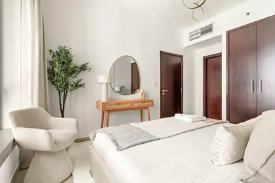 a bedroom with a bed and a chair and a mirror at Silkhaus Elite 1BDR at 29 Boulevard Downtown in Dubai