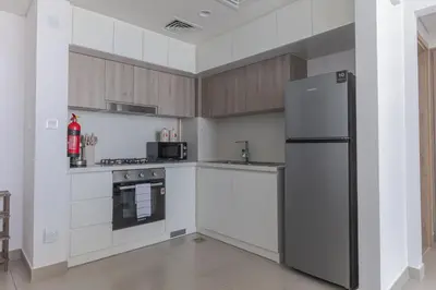 a kitchen with white cabinets and a refrigerator at Beautiful view, fully-equipped apartment in Dubai