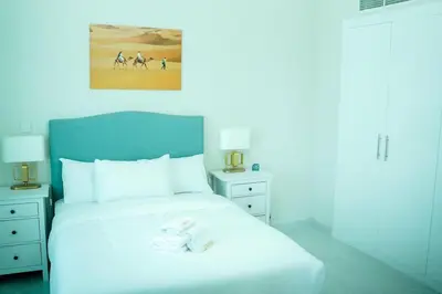 a bedroom with a white bed with a blue headboard at Zapbed House-Cozy 2 BR Apartment In The Greens Golf View in Dubai