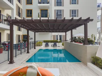a pool with a pergola next to a building at High-End Luxury 1BR in Port De La Mer near J1 Beachfront, Dubai in Dubai
