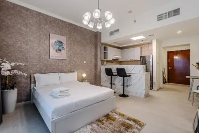 a bedroom with a white bed and a kitchen at Stylish Studio apartment in Downtown Dubai in Dubai