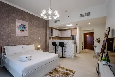 a bedroom with a white bed and a kitchen at Stylish Studio apartment in Downtown Dubai in Dubai