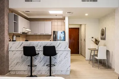 a kitchen with a counter and two chairs and a table at Stylish Studio apartment in Downtown Dubai in Dubai