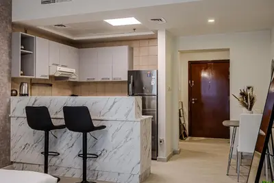 a kitchen with two bar stools and a counter at Stylish Studio apartment in Downtown Dubai in Dubai