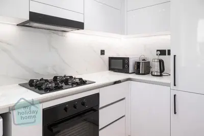 a white kitchen with a stove and a microwave at Fully furnished with stunning panoramic view in Dubai