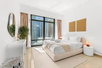 a white bedroom with a large bed and large windows at Waves- Cozy 1BR Lakefront Stay in JLT in Dubai