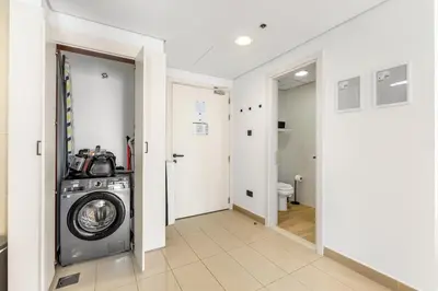 a washing machine in a hallway with a bathroom at Waves- Cozy 1BR Lakefront Stay in JLT in Dubai