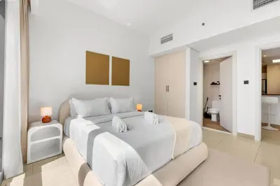 a white bedroom with a large bed and a bathroom at Waves- Cozy 1BR Lakefront Stay in JLT in Dubai