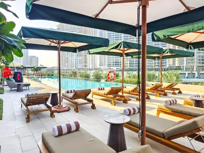 a pool with lounge chairs and umbrellas at Beach Escape 1BR-Vida Residences Creek Beach in Dubai