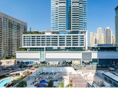 a large white building with a parking lot in a city at Female - Girls Joyful Journeys - girls only bedspace in Dubai