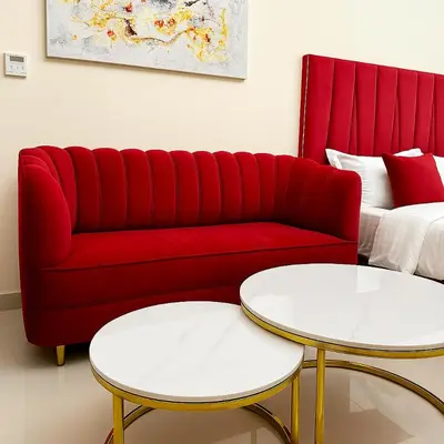 a red couch with two tables in a living room at Comfy Studio in JVC Great Location Fast Wi-Fi in Dubai