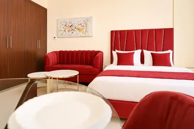 a bedroom with a red bed and a red chair at Comfy Studio in JVC Great Location Fast Wi-Fi in Dubai