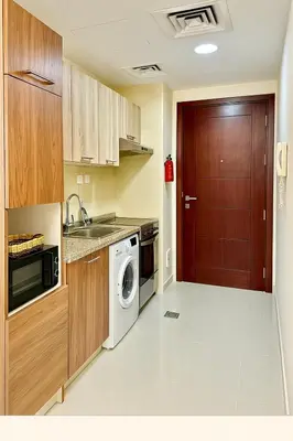 a kitchen with a washing machine and a wooden door at Comfy Studio in JVC Great Location Fast Wi-Fi in Dubai