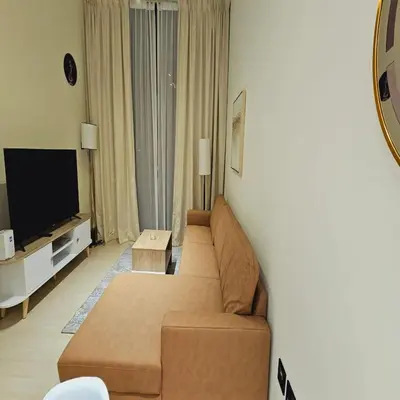 a living room with a couch and a television at Luxurious Belvilla 1BR JVC with Pool, Gym & BBQ Access in Dubai