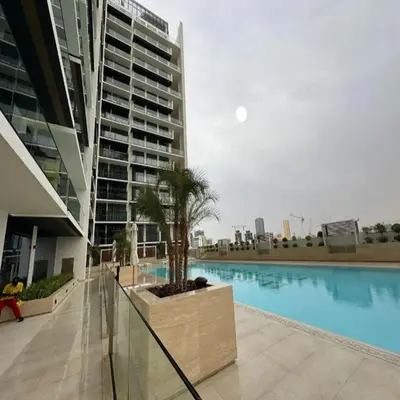 a large building with a swimming pool in front of a building at Luxurious Belvilla 1BR JVC with Pool, Gym & BBQ Access in Dubai
