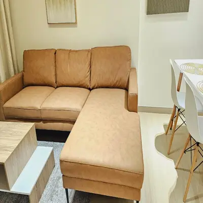 a living room with a brown couch and a table at Luxurious Belvilla 1BR JVC with Pool, Gym & BBQ Access in Dubai