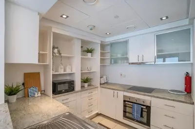 a large white kitchen with white cabinets and appliances at Elegant 1BR At Sanibel Tower park Island Tower Dubai Marina by al sarya holiday homes in Dubai