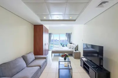 a living room with a couch and a tv at Chill Studio with Balcony and Pool View in Dubai